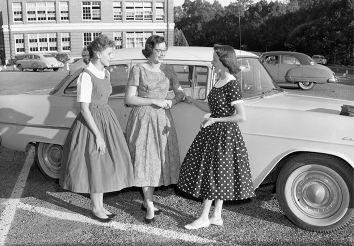 Three women in the 1950s standing in front of car